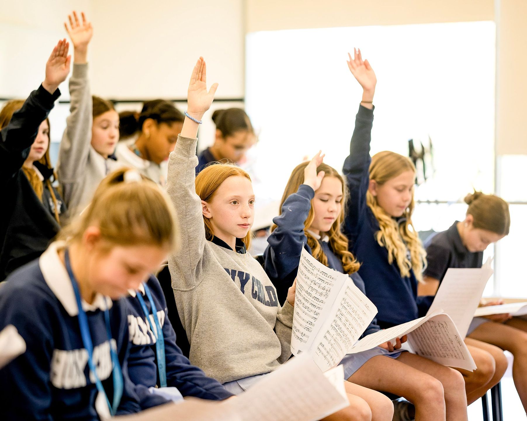 Middle School students raising their hands during class at Holy Child.